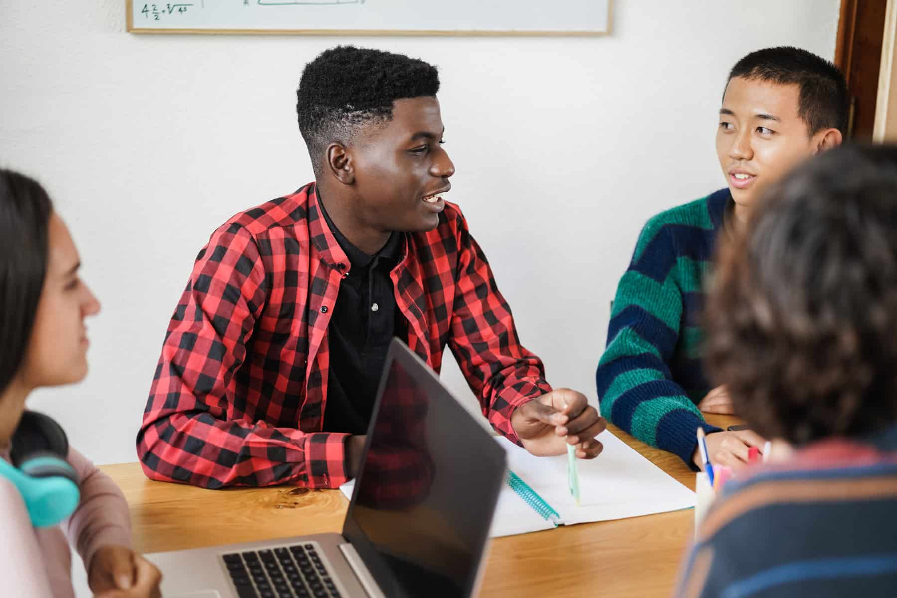 Multiracial students using laptop computer for project research while studying together at school - Focus on african boy face